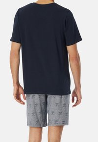 Camiseta de manga corta azul marino para hombre combinada con pantalones cortos gris claro con un patrón de palmeras. Mezcla de algodón con un corte relajado.