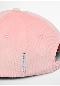 Różowa czapka z sztruksu z fakturowaną tkaniną, z przeszywanym guzikiem na górze, haftowanymi oczkami wentylacyjnymi oraz firmową metką z boku.