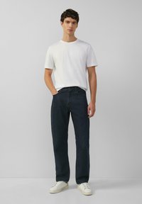 Witte katoenen T-shirt, ontspannen pasvorm, gecombineerd met donkerblauwe denim jeans, rechte pijpen, minimale stiksels en witte sneakers.