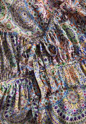 Bunte Stoffe mit komplizierten Blumen- und geometrischen Mustern in Lila, Orange, Grün und Blau, mit geraffter Textur und Bändern.