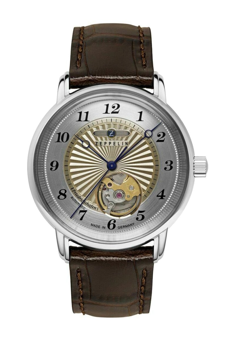Mechanical watch with a silver dial, brown leather strap, blue hands, and gold accents. Features a visible movement and prominent numbers.