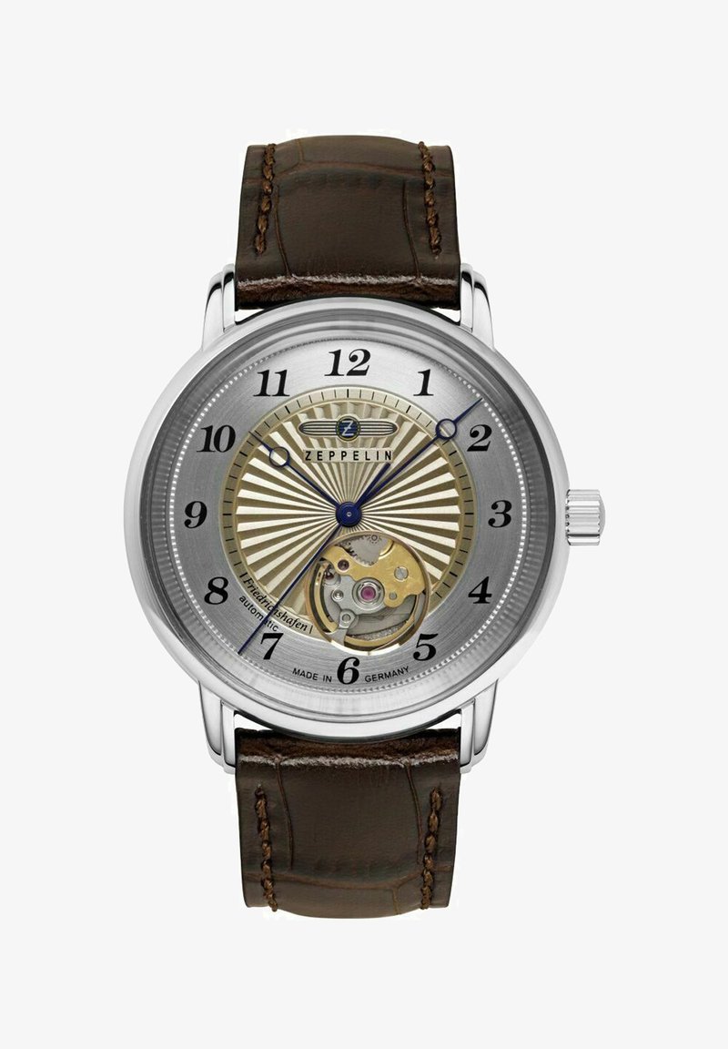 Mechanical watch with a silver dial, brown leather strap, blue hands, and gold accents. Features a visible movement and prominent numbers.