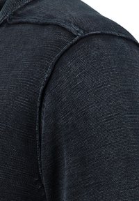 Tela de hombro azul oscuro texturizada con detalles de costura visibles y una superficie suave. Vista en primer plano centrada en el color y la textura.