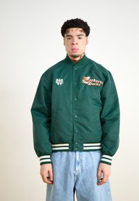 Grøn satin bomberjakke med trykknaplukning, striped ærmer og et broderet "Carhartt Ducks" logo på brystet.