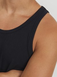 Débardeur sans manches noir en coton, présentant une texture lisse et un col rond, ajusté aux épaules et aux bras.