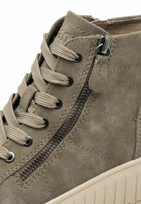 Baskets montantes en suede kaki avec une finition texturée, dotées d'une fermeture éclair sur le côté et de lacets ronds, reposant sur une semelle en caoutchouc crème.