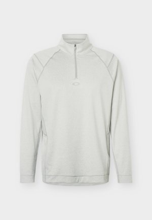 Svijetlosivi pulover dugih rukava s četvrtastim zatvaračem i uspravnim ovratnikom, s diskretnim detaljima šavova i malim logotipom na prsima.