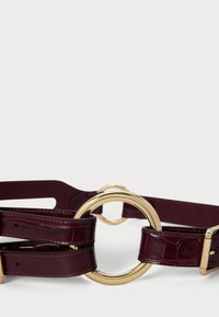 Burgundowa skórzana pasek z błyszczącą, złotą okrągłą klamrą. Posiada teksturowany wzór krokodyla oraz regulowaną długość z pewnym metalowym zapięciem.