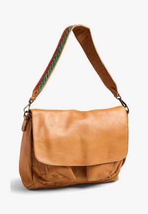 Sac d'épaule en cuir fauve avec une large bandoulière ornée de détails tissés rouges et verts, ainsi que des attaches à boucle en métal.