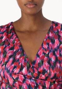 Rochie florală cu un tipar vibrant în nuanțe de roz și violet, cu accente verzi. Design cu decolteu în V și detalii din material gathered. Textură netedă.