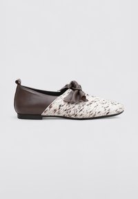 Des ballerines en cuir avec un dessus tacheté blanc et brun et un talon en cuir brun foncé, dotées d'un accent de nœud à l'avant.