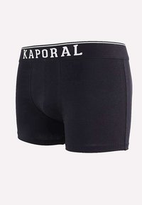 Boxer shorts noirs en matériau doux semblable au coton, avec une large ceinture élastique portant le logo "KAPORAL" en blanc.