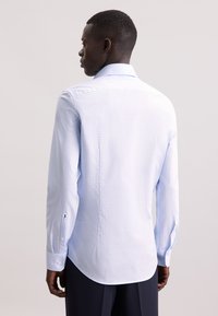 Lichtblauw geruit overhemd van katoen. Heeft lange mouwen, een gebogen zoom en knoopmanchetten met een klein merklogo-detail.