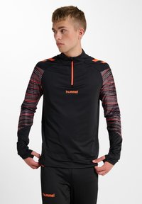 Svart träningspullover med en fjärdedel dragkedja, med mångfärgade mönstrade ärmar och logotyp. Tillverkad av lätt, elastiskt material.