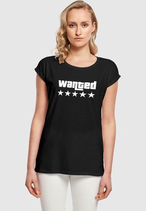 Schwarzes T-Shirt mit kurzem, aufgerolltem Ärmel, das in fetter weißer Schrift "gesucht" und fünf weiße Sterne darunter zeigt. Glatter Stoff.