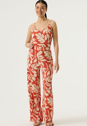 Mono estampado en rojo y crema con tirantes finos, tejido texturizado, diseño de pierna ancha y cintura con cinturón.