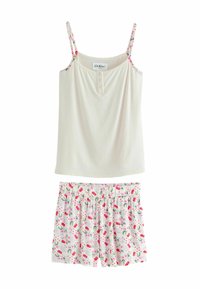 Camisole crème clair avec des bretelles florales et un devant boutonné, associé à un short blanc avec un motif de cerises roses et de feuilles.