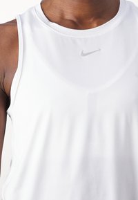 Camiseta deportiva sin mangas de Nike en blanco, con una tela suave y ligera, cuello redondo y un sutil logo tonal en la zona del pecho.