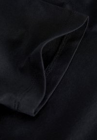 Black fabric with a smooth texture, featuring a folded edge and visible stitching detail. The material appears soft and flexible.