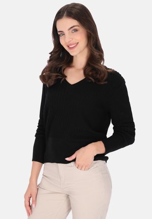 Pulover negru cu guler în V și dungi, cu mâneci lungi, țesătură texturată și tiv ușor scurtat, purtat cu pantaloni bej deschiși.