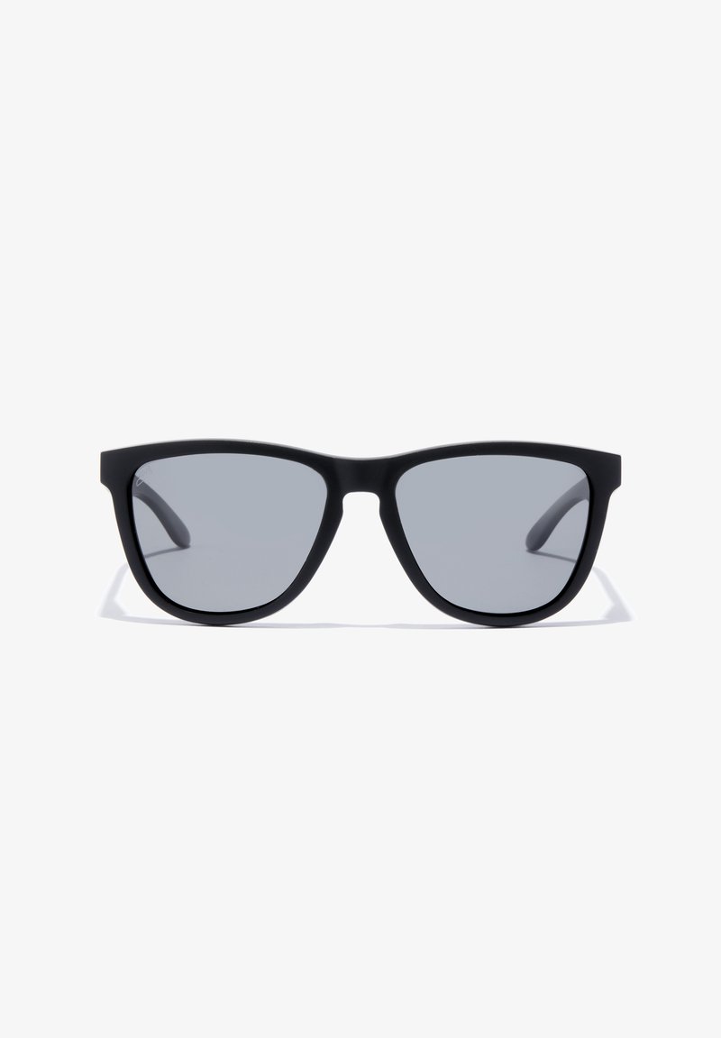 Mustad musta raamiga päikeseprillid, hallid objektiivid, nurkadega kuju ja saledad varred. Pole nähtavaid logosid ega kaunistusi.