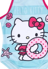 Costume da bagno con design di Hello Kitty, azzurro chiaro con accenti rosa, un salvagente a pois e illustrazioni di conchiglie e stelle marine.