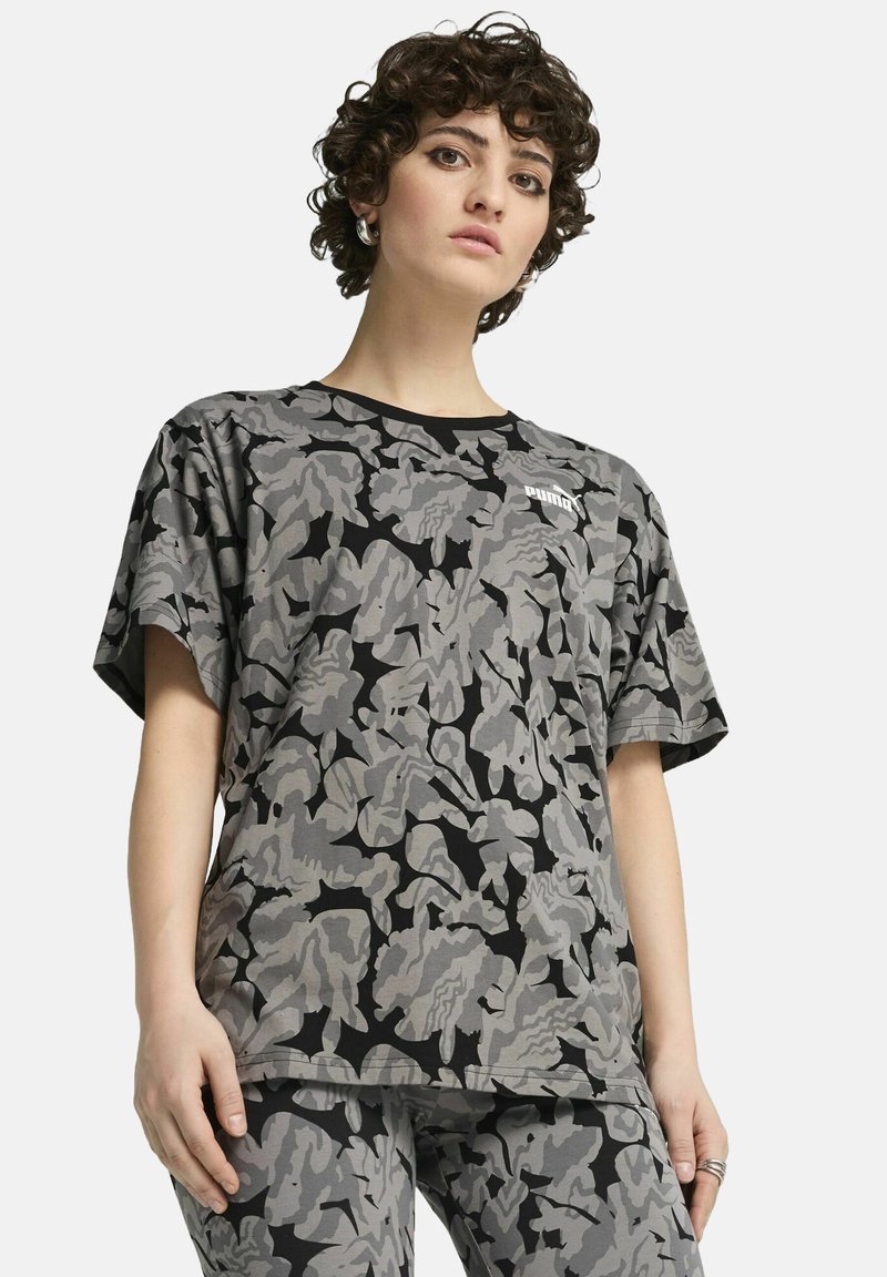 Camiseta de manga corta con patrón de camuflaje gris, con un borde negro y un pequeño logotipo blanco en el lado izquierdo. Hecha de una tela suave y texturizada.