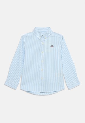 Camisa de manga larga abotonada con rayas azul claro y blancas, con cuello y pequeño logo bordado en el pecho izquierdo.