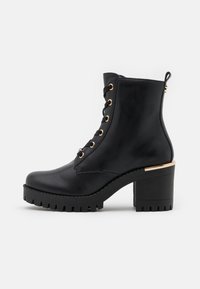 Bottines en cuir noir avec une semelle texturée, des accents en métal doré, un design à lacets et un talon épais.