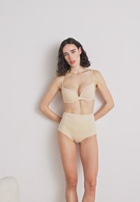 Beige bra with soft cups and adjustable straps paired with high-waisted beige underwear. Smooth fabric with a seamless design.