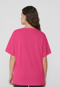 Fuchsiové oversized tričko vyrobené z měkké bavlny, s kulatým výstřihem a krátkými rukávy, s jednoduchým designem vzadu.