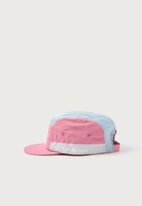 Gorra rosa y azul con visera plana, paneles de malla y un acento reflectante en gris. Presenta el logo de "New Balance" en un lado.