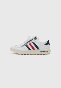 Vita lädersneakers med marinblå och röda ränder, perforerade detaljer på tån och en texturerad gummisula med en synlig varumärkeslogotyp.