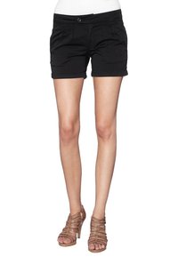 Shorts en coton noir avec une coupe ajustée, dotés de poches avant et d'un ourlet roulé. Associés à des sandales à talons hauts à lanières beiges.