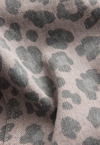 Light brown fabric with large irregular dark gray leopard print spots and visible diagonal weave texture.