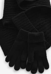 Svart stickad ullscarf och vantarset. Vantarna har en manchet-design med fem fingrar, slät textur och en jämn svart färg.