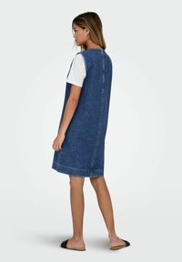 Denim A formos su apvaliu iškirpimu, be rankovių dizainu ir neapdorotu kraštu. Yra mėlynos nuplautos medžiagos su matomomis siūlių detalėmis.