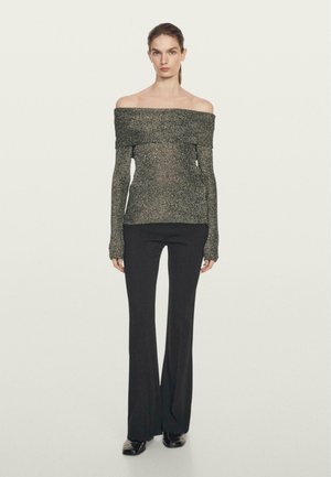 Haut à manches longues métalliques noires, cœur dénudé, avec un tricot texturé, associé à un pantalon noir évasé ajusté et des chaussures noires brillantes.