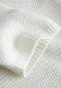 Tissu tricoté blanc à côtes, avec une texture douce et un motif subtil, présentant un bord replié pour un détail accentué.