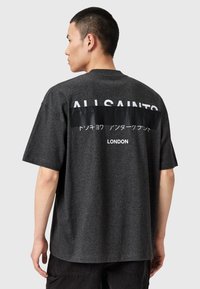 T-shirt gris à manches courtes avec une coupe décontractée, présentant un design rectangulaire noir au dos avec un texte blanc indiquant "ALLSAINTS LONDON."