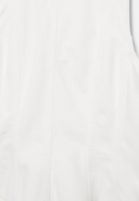 Vêtement blanc sans manches avec des détails de coutures verticales et un tissu légèrement texturé.