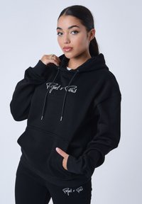 Zwarte hoodie met witte geborduurde logo. Voorzien van een voorzak, een capuchon met trekkoord en een zachte textuur. Gecombineerd met bijpassende zwarte leggings.