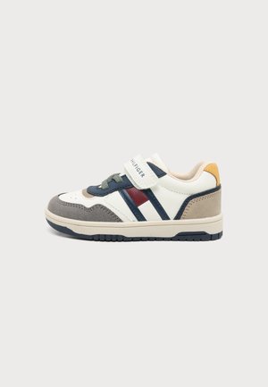 Baskets enfant avec des panneaux blancs, bleu marine, gris et rouges, des lacets gris et une bride Velcro blanche étiquetée Tommy Hilfiger.