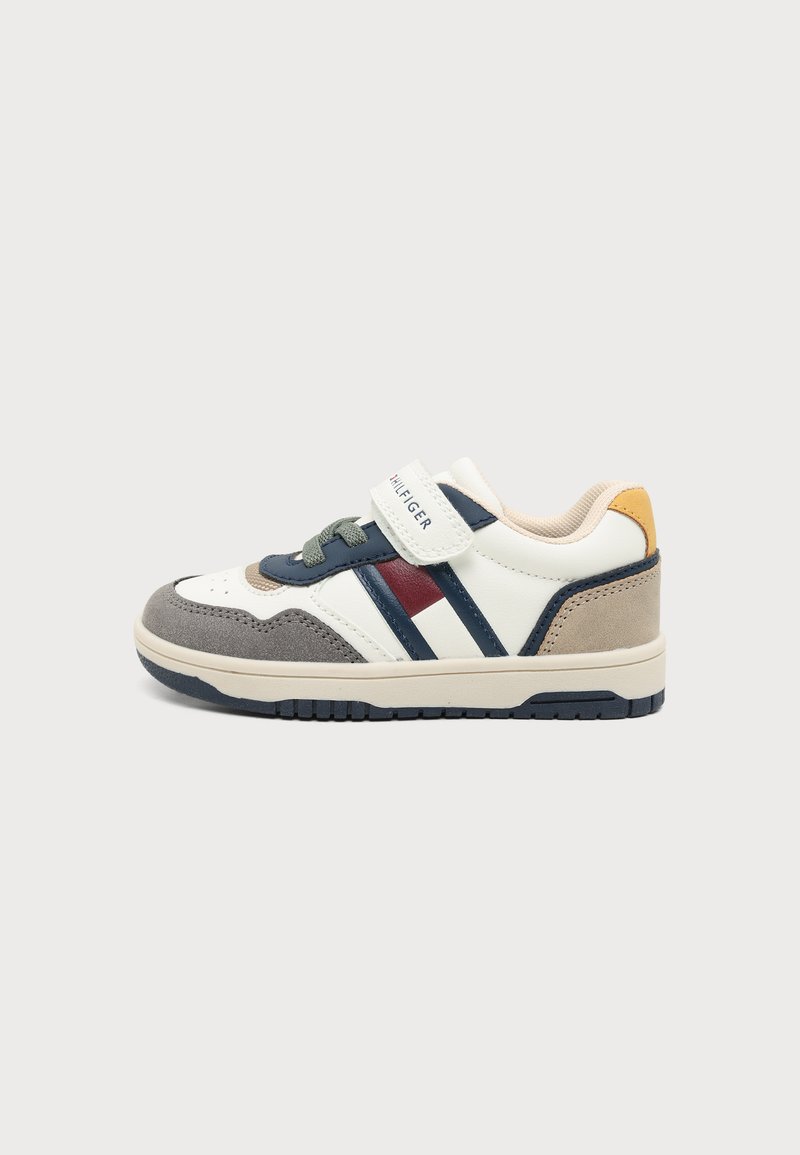 Baskets enfant avec des panneaux blancs, bleu marine, gris et rouges, des lacets gris et une bride Velcro blanche étiquetée Tommy Hilfiger.