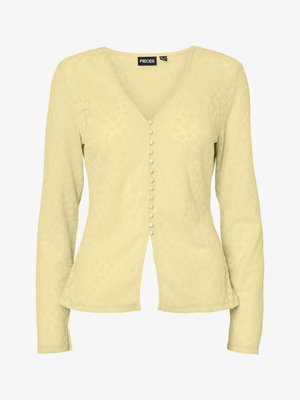 Blouse pour femme à manches longues de couleur jaune clair avec col en V et boutons recouverts de tissu sur le devant, légèrement cintrée à la taille.