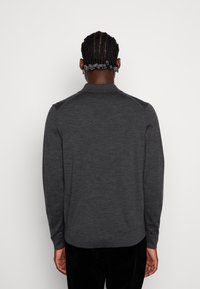 Mörkgrå stickad tröja med krage, långärmad och ribbad fåll. Har axelaccents, slät textur och en figurnära form.