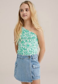 Top verde con estampado floral de un hombro, combinado con una falda de mezclilla azul clara con un bolsillo lateral y cierre de botón.