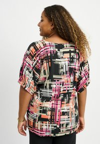 Sort bluse med abstrakte mønstre i pink, orange og beige. Har korte puffærmer og knapdetalje ved nakken bagpå. Letvægtsstof.