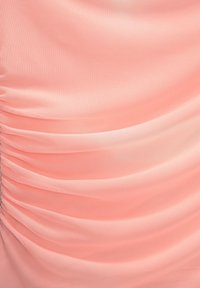 Tissu couleur pêche avec un froncage doux et texturé, présentant un léger éclat et créant de délicates pliures sur la surface.