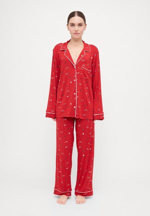 Red pajama set featuring long-sleeve top and matching pants. Material is soft with a floral pattern, accented by white piping along edges.